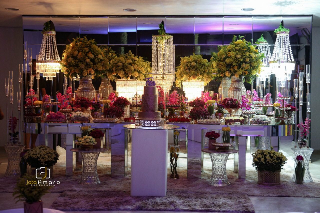 Mesa de doces com lustres de cristal e flores amarelas