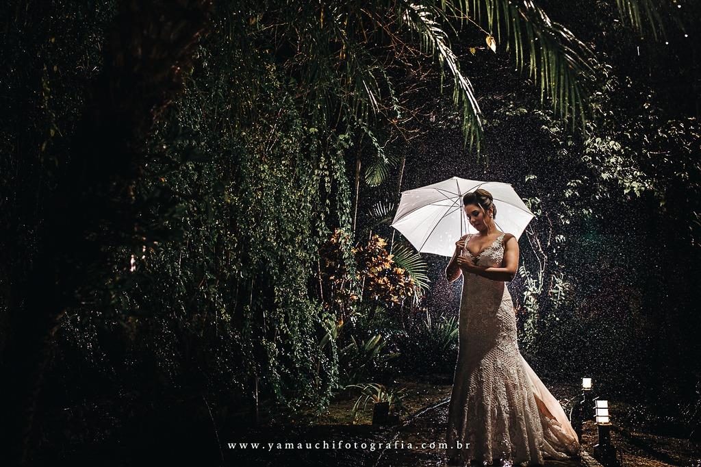 Noivos sob guarda-chuva no jardim à noite